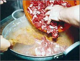 タマネギ・にんにく・調味料などの中に肉を入れている写真