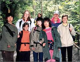 緑の中で記念撮影をする現地の学生と中学生の写真