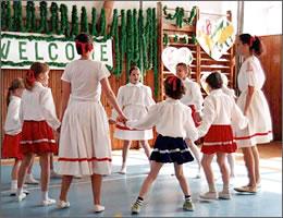 民族衣装を着て輪になって踊る現地の年齢が様々な学生たちの写真