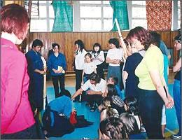 剣道着を着ている中学生とその様子を見る現地の学生と先生の写真