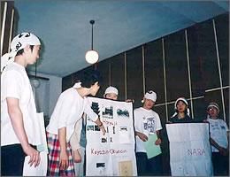 模造紙を使って説明をする手拭いを頭に巻いた中学生の写真