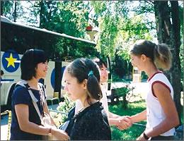 バスの前で握手をする現地の学生たちと中学生の写真