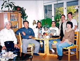 リビングらしき部屋で現地の家族と記念撮影している訪問団の写真