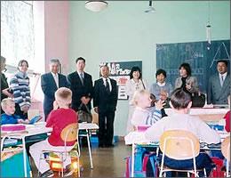 黒板の横で授業風景を笑顔で見学する訪問団の写真