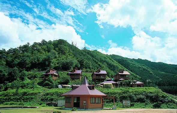 緑の山にバンガローが建ち並ぶ宮の向いキャンプ場の写真