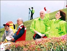 緑の服を着ている2人と、赤い服を着ている一人と、グレーの服を着ている一人が、遠くを見ている写真