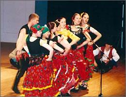 舞台上で華やかな赤いスカートの衣装で踊る女性たちの写真