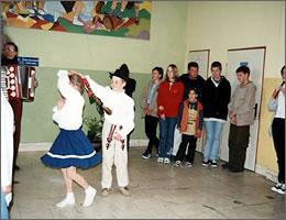 アコーディオンの演奏で民族衣装を着て踊る現地の子供ふたりと、それを見ている学生たちの写真