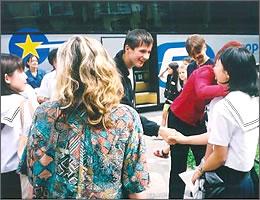 バスの前で握手をする現地の学生と中学生の写真