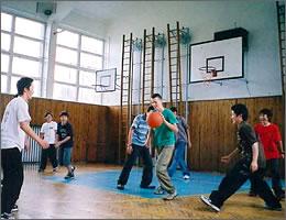 現地の学生たちと一緒に体育館でバスケットボールをする中学生の写真